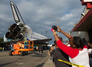 Spectators are seen photographing space shuttle Endeavour as it passes by on its way to its new home at the California Science Center, Friday, Oct. 12, 2012, in Inglewood.