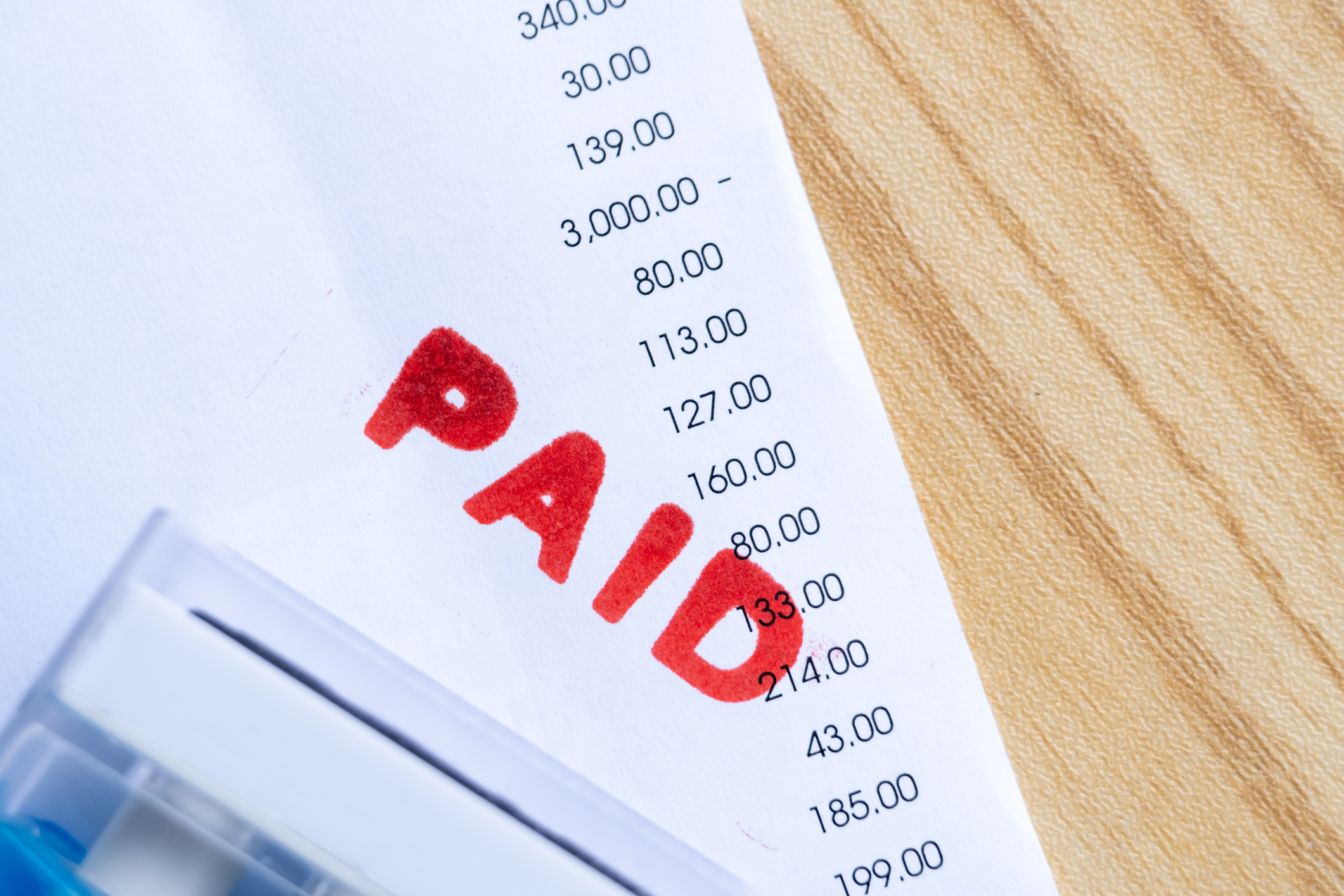Close up of red paid stamp on bill receipt document with numbers, symbolizing payment, finance, and accounting.