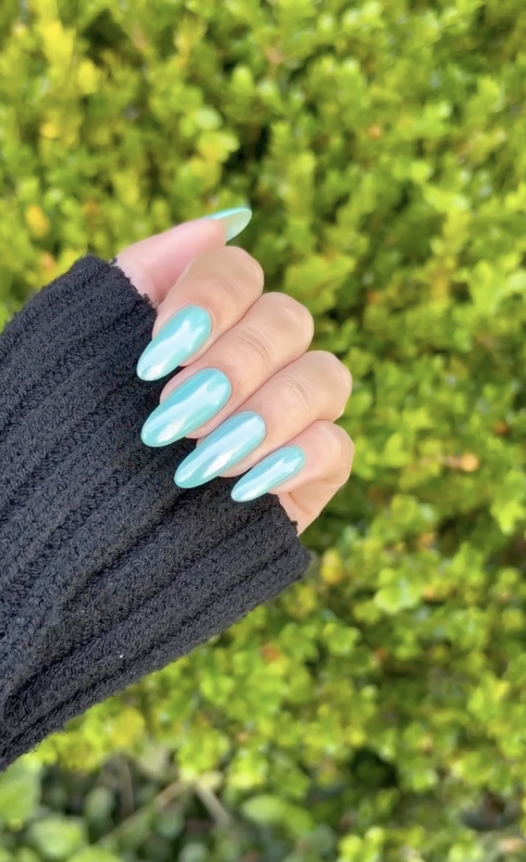 a person wearing teal chrome nails