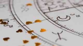 Detail of printed natal chart with astrology moon and heart shaped golden sequins.