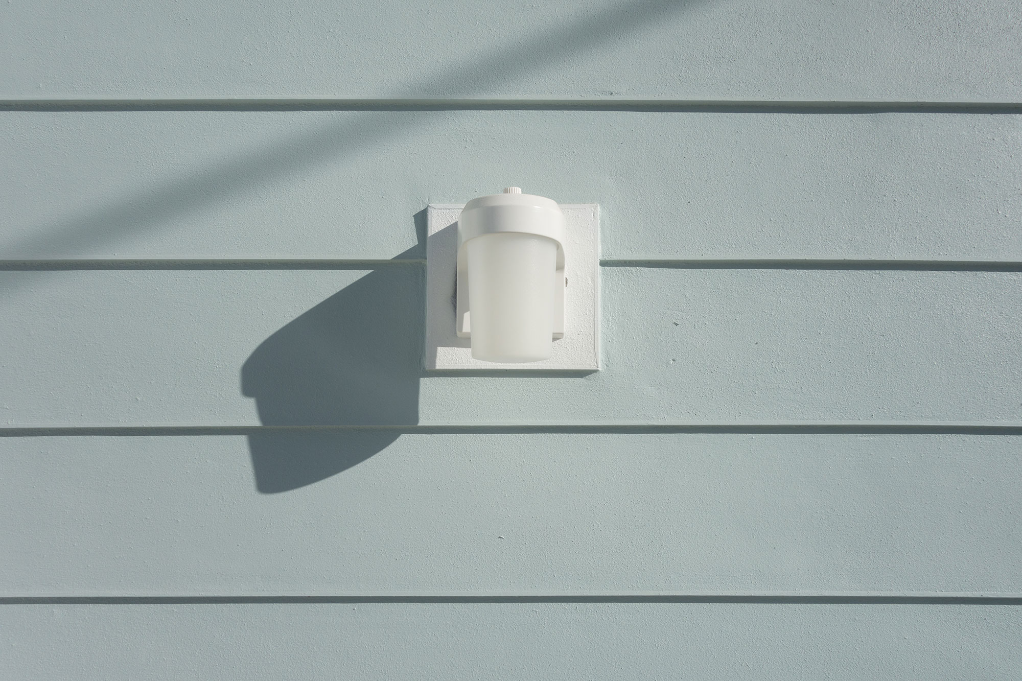 A PIR light on the external painted wall of a timber shed