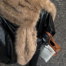 @rikkekrefting in a black leather jacket, a fur scarf, and a colored bag. 