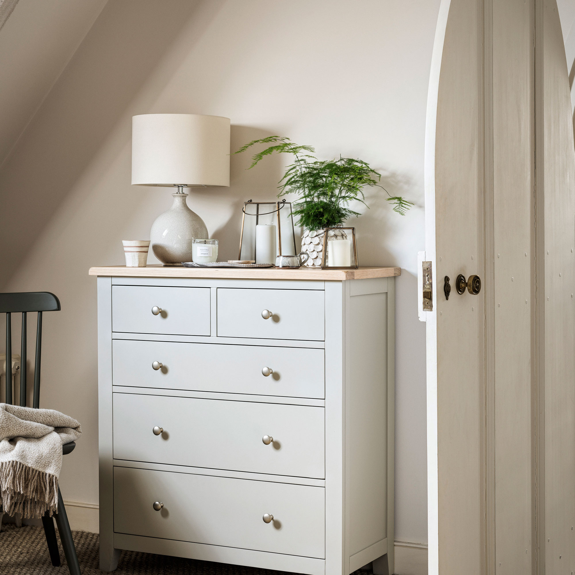 White chest drawers with a white wall and white lamp