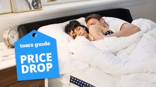 A couple lie asleep on the WinkBed mattress, with a Tom's Guide price drop deals graphic (left)