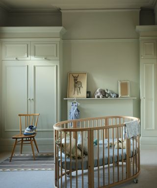 nursery room with pale green walls, wooden cot and chair