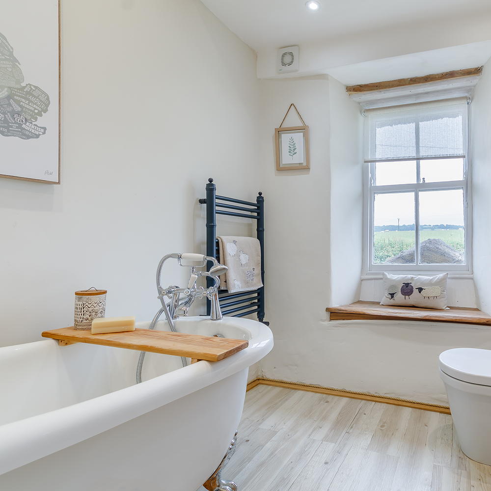bathroom with wooden flooring and white bathtub