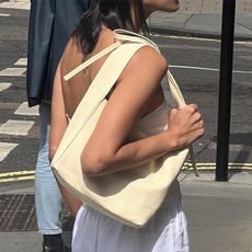 Woman stands on street and carries yellow handbag