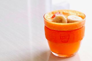 Papaya and banana smoothie in a glass with chopped banana topping