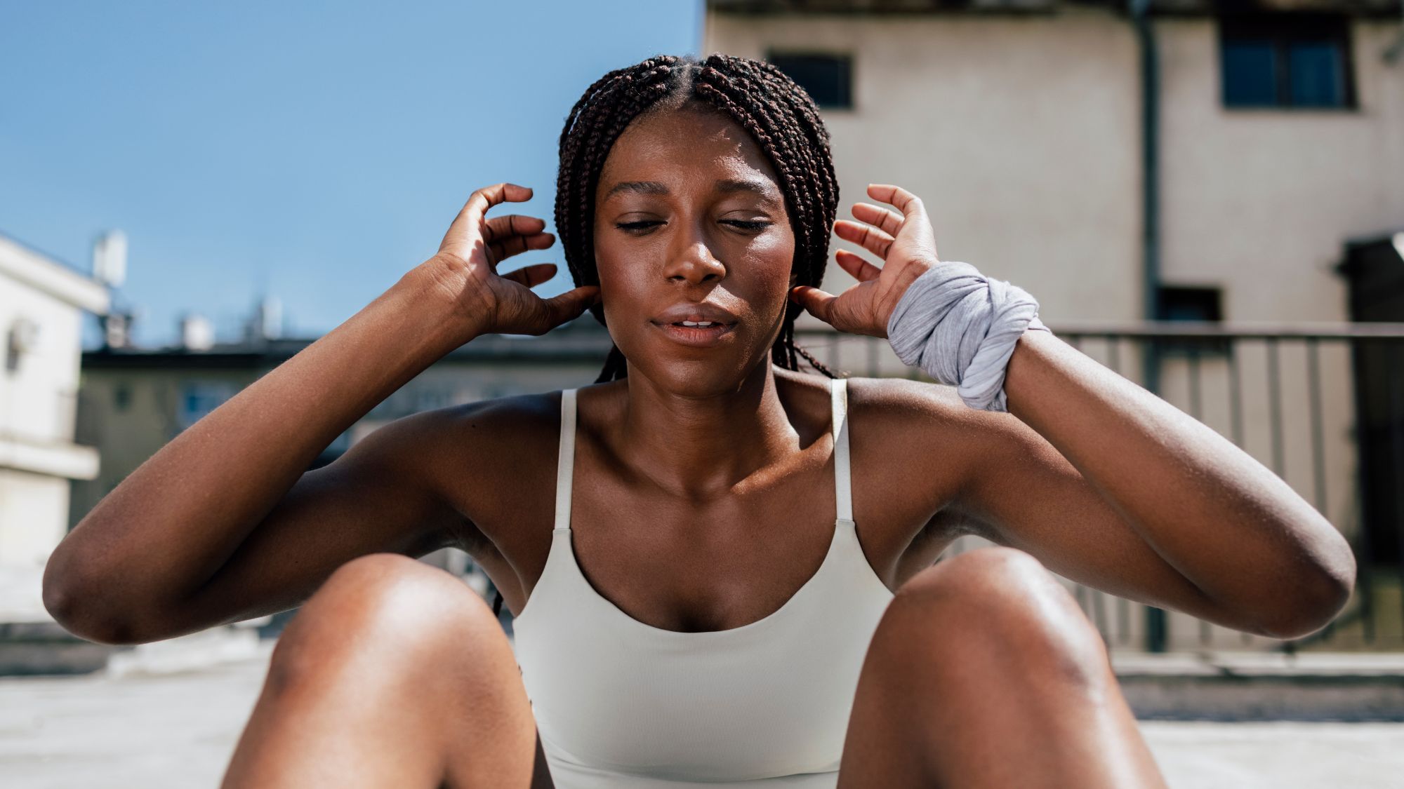 A woman doing a sit up outside: Workout on a roof, wearing a sports bra
