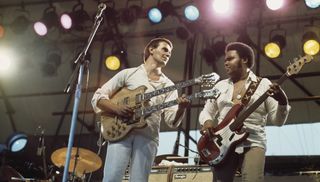 John McLaughlin playing a double-necked guitar, and and bassist Ralphe Armstrong during a live concert performance with the Mahavishnu Orchestra, in Central Park, circa 1970. 