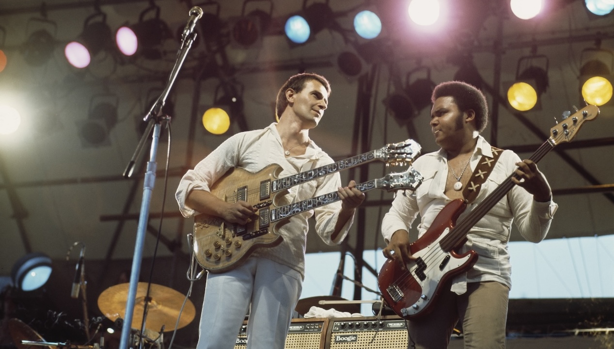 John McLaughlin playing a double-necked guitar, and and bassist Ralphe Armstrong during a live concert performance with the Mahavishnu Orchestra, in Central Park, circa 1970. 