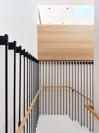 Staircase with black vertical elements in white and light wood background at Four One Nine by Síol Studios