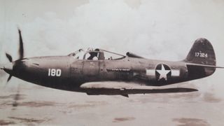 We see a black-and-white photo of a P-39 Bell Airacobra flying in the air.