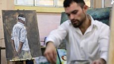 A Syrian artist works on portraits of people imprisoned by the former dictator, Bashar al-Assad, during his trial in absentia