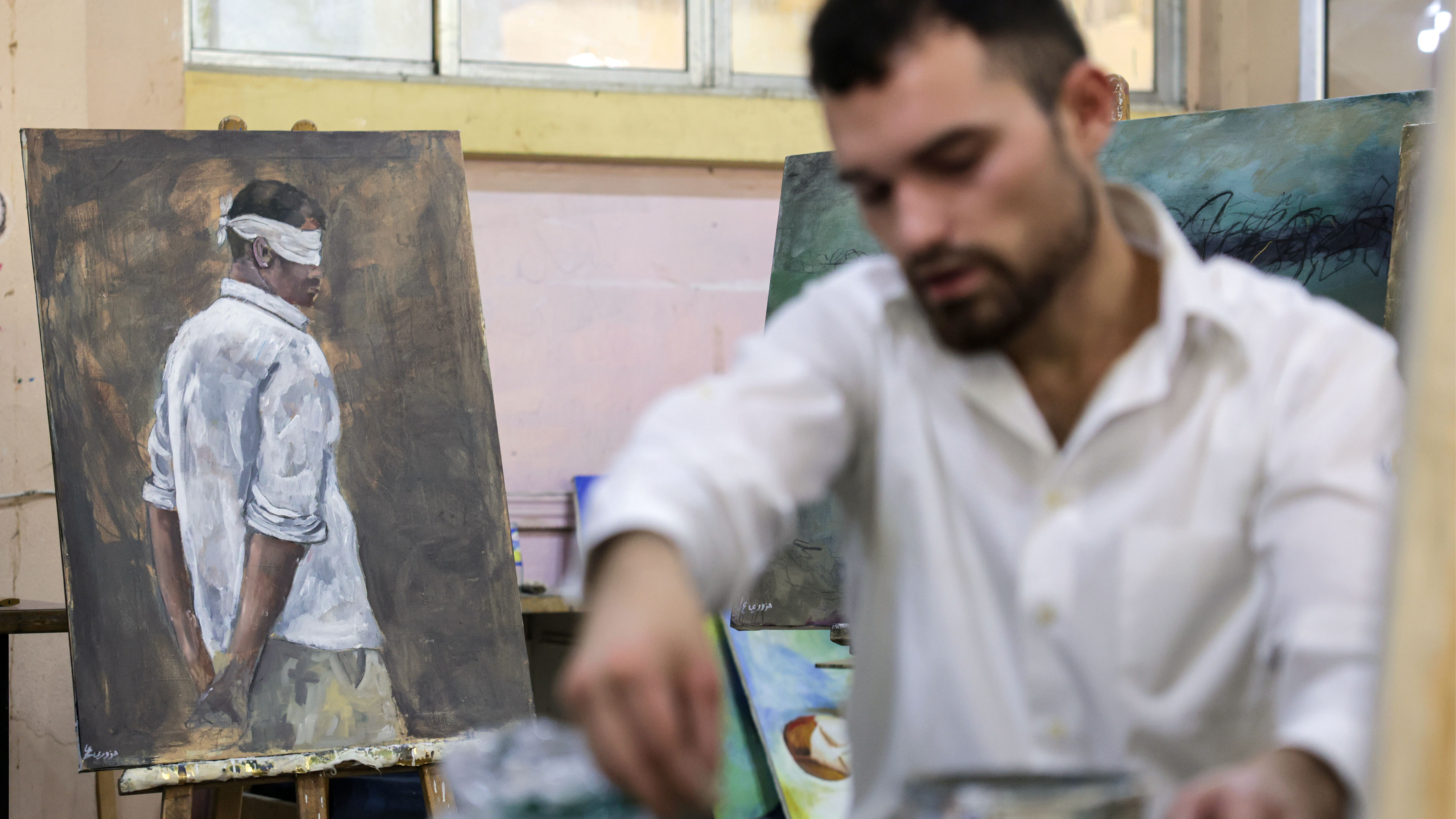 A Syrian artist works on portraits of people imprisoned by the former dictator, Bashar al-Assad, during his trial in absentia