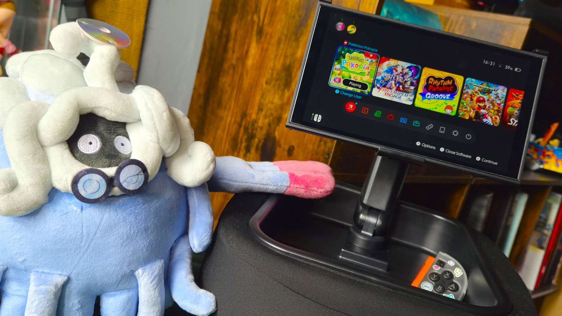 Photo of a plush of Professor Tangrowth from Pokemon Pokopia sitting next to the Lululook Switch 2 Gaming Pillow.