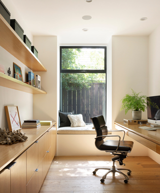 Oak hue WFH space with large window, wooden desk and black modern office chair