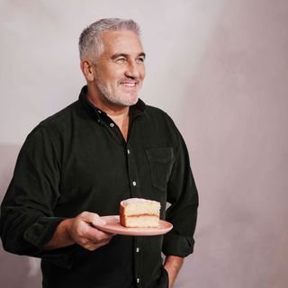 Paul Hollywood standing with a slice of cake