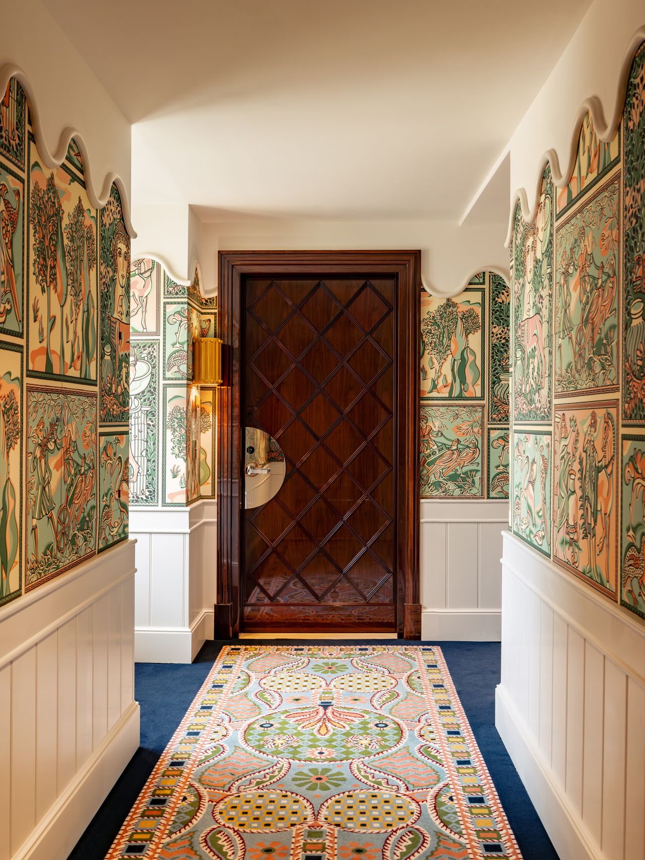 The corridor of a maximalist hotel features rich wall and floor tapestries