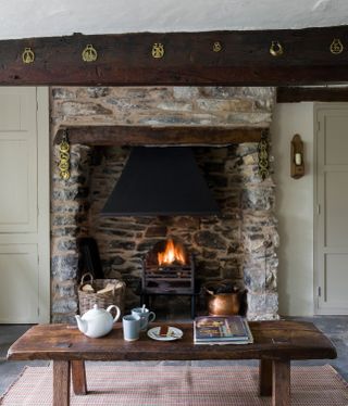 stone fireplace with lit fire and tea set