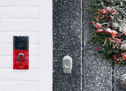 A Christmas themed ring doorbell on a snowy porch