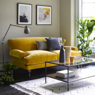 A living room with a yellow velvet sofa