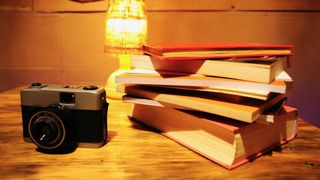 A retro camera beside a pile of books on a table