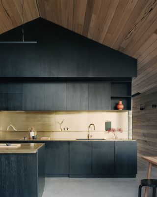A black kitchen with gold backsplash