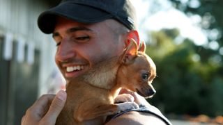 Smiling man carrying chihuahua on shoulder