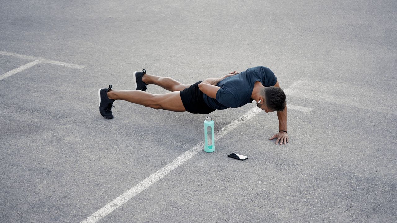 Man performs a one-handed push up outside