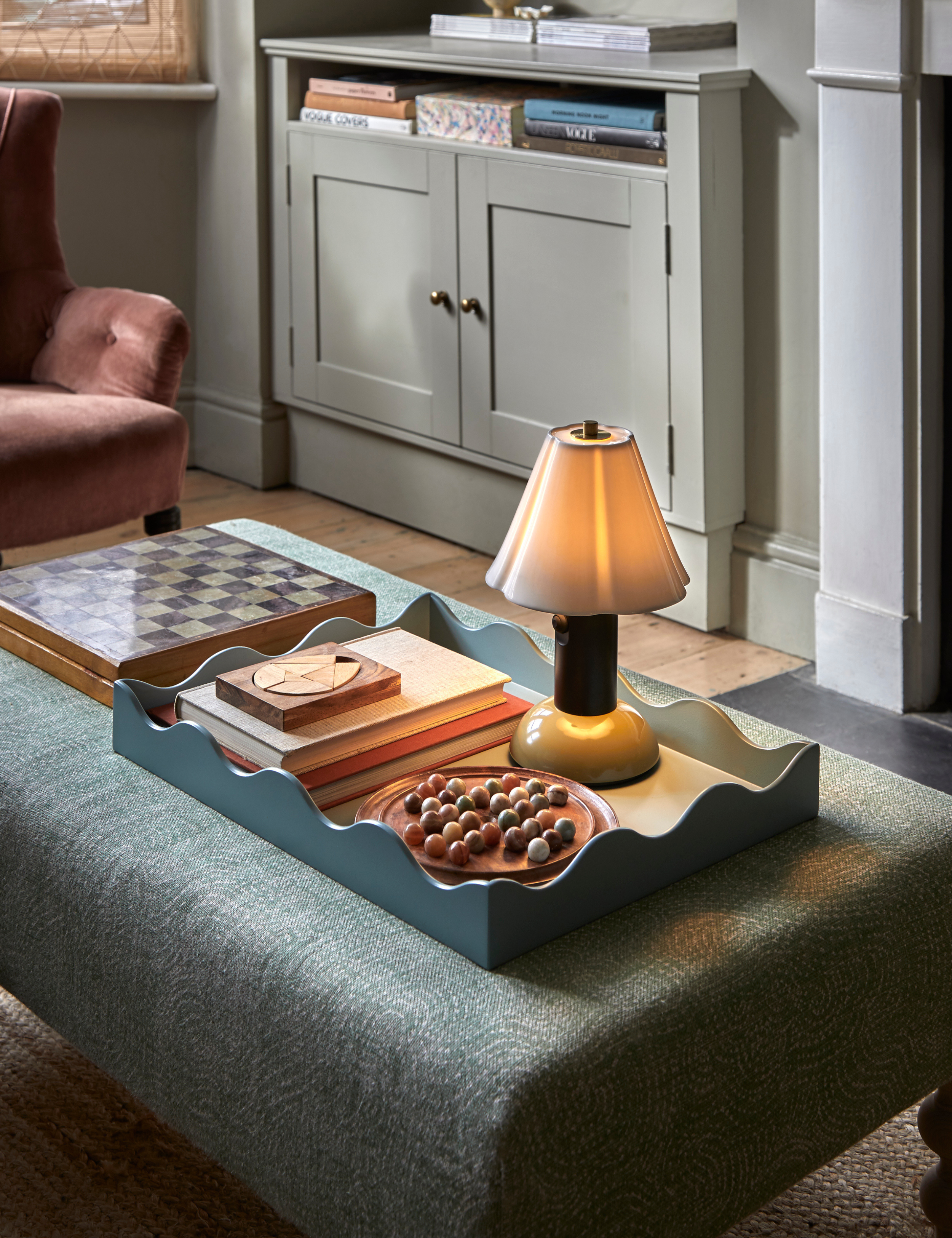 Original BTC table lamp and scalloped tray resting atop a blue upholstered fabric ottoman.