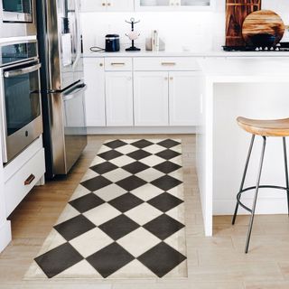 A black and white checkerboard vinyl kitchen rug on light wooden floor