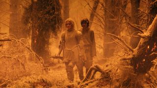 Galadriel and Theo walking through a forest that was on fire.