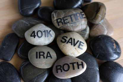 Smooth rocks with the words retire, 401K, IRA, roth and save on them arranged in a zen-like way.
