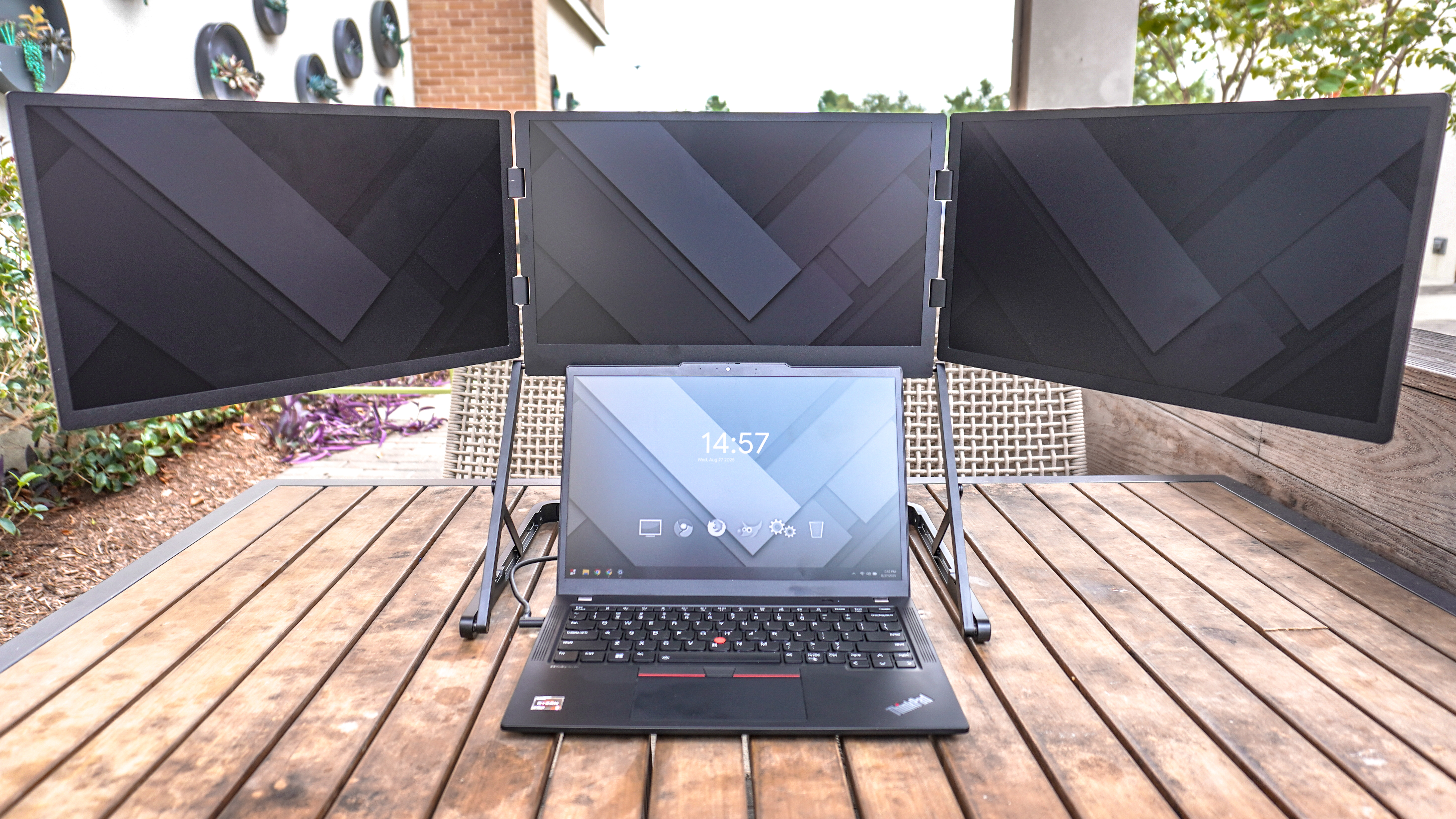 The Aura Triple Aero 15.6 Pro Max triple-display portable monitor connected to a laptop on a table outside