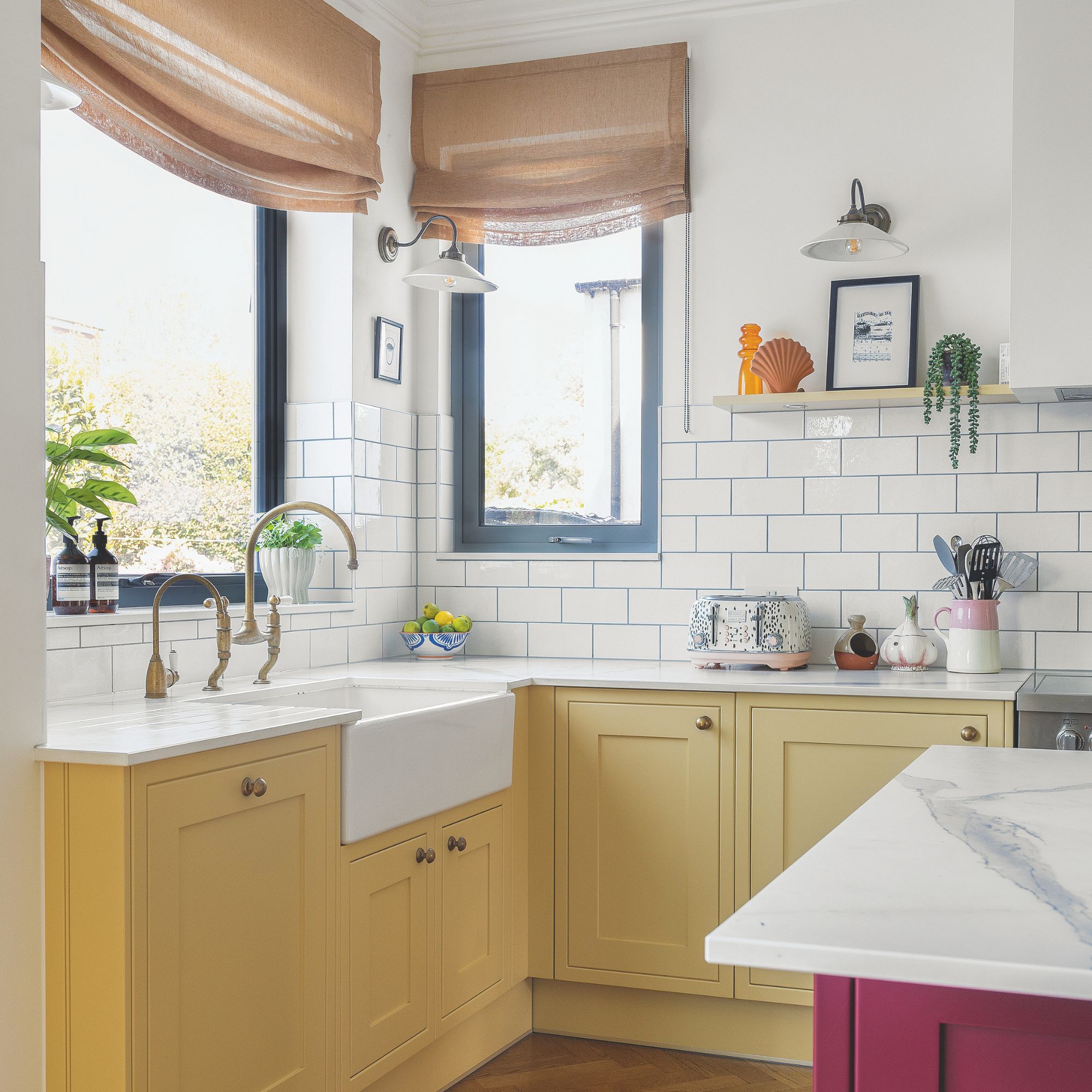 White kitchen with white metro tiles on the wall and a white worktop. The under-counter cabinets are bright yellow