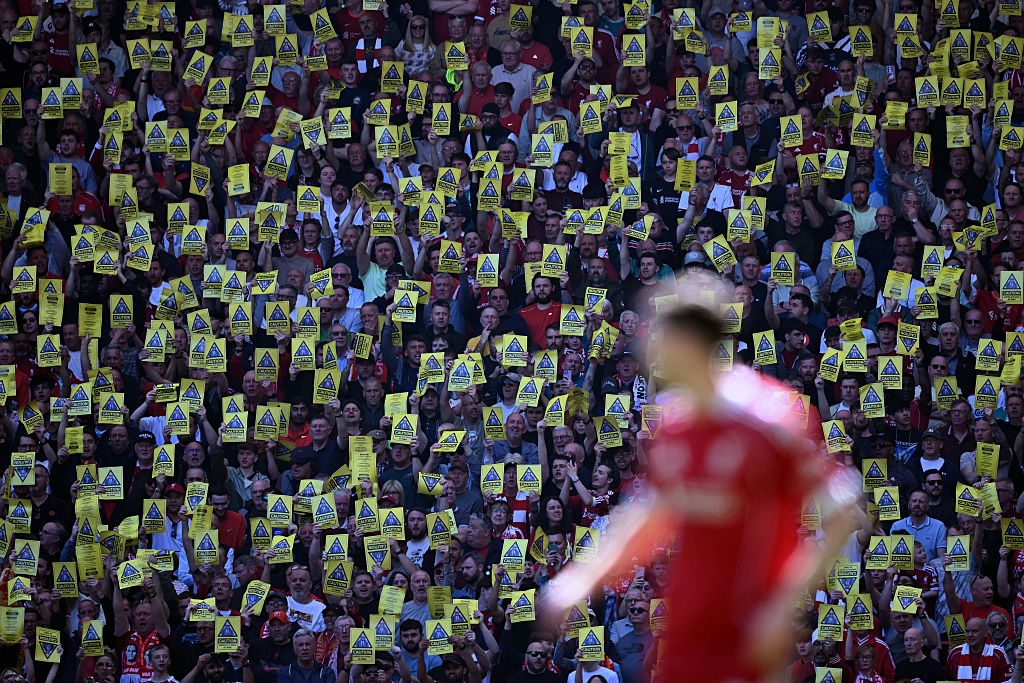 Liverpool fans hold aloft leaflets and banners critical of Liverpool's owners during the English Premier League football match between Liverpool and Crystal Palace at Anfield