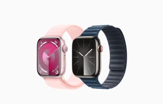 En rosa och en mörkgrå Apple Watch 9 visas upp mot en vit bakgrund.
