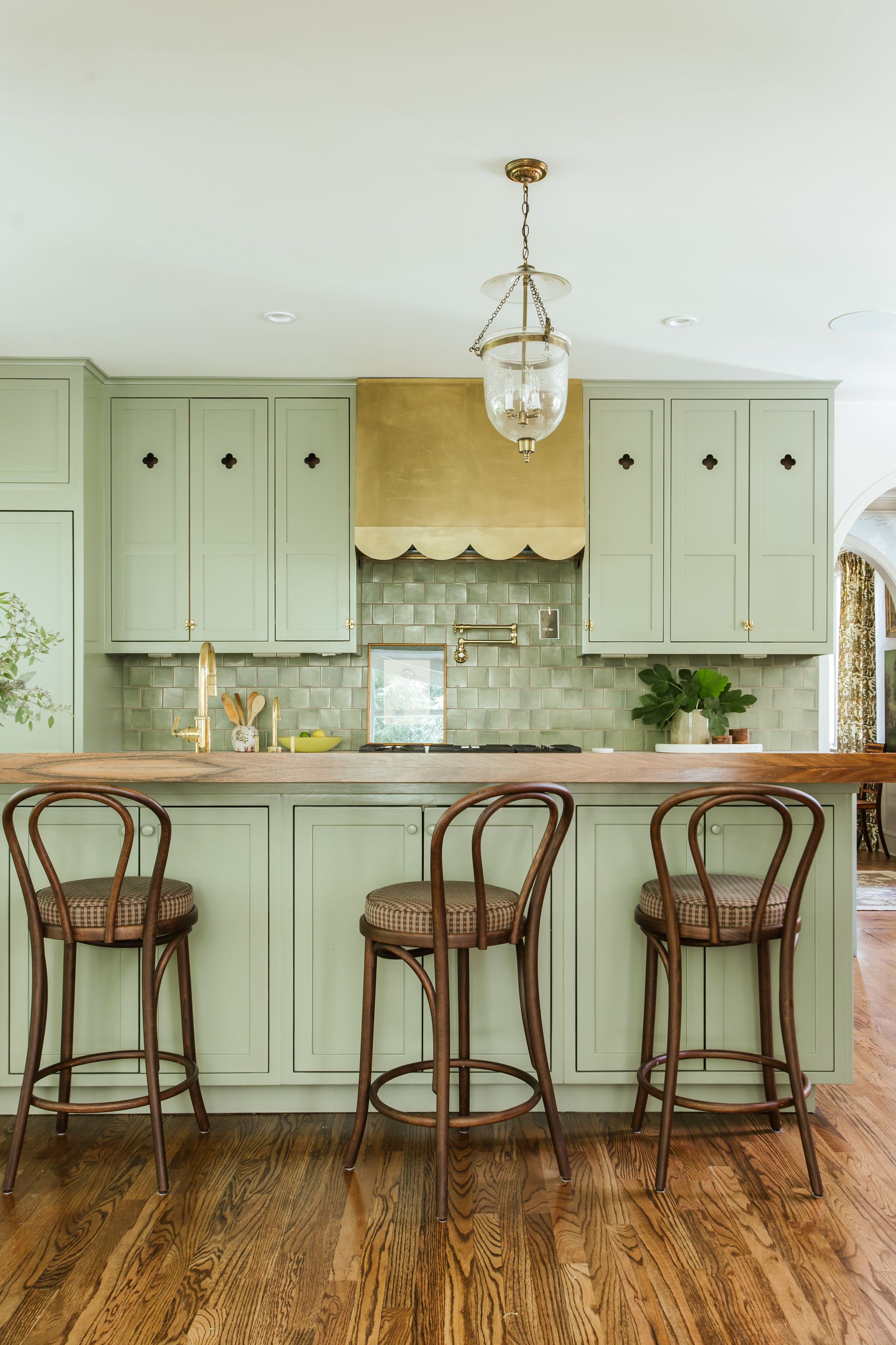 a grey-green kitchen with a scalloped cooker hood