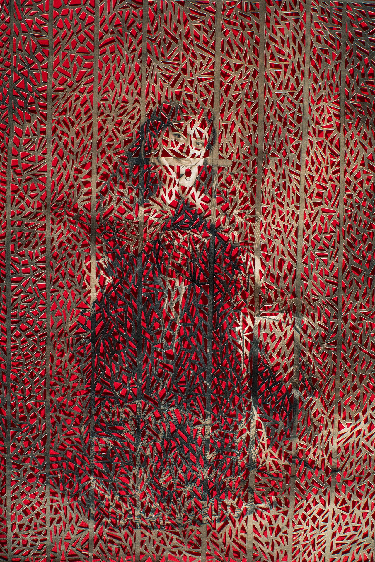 A woman sitting down in traditional attire, having her hands on her face, surrounded by intricate patterns