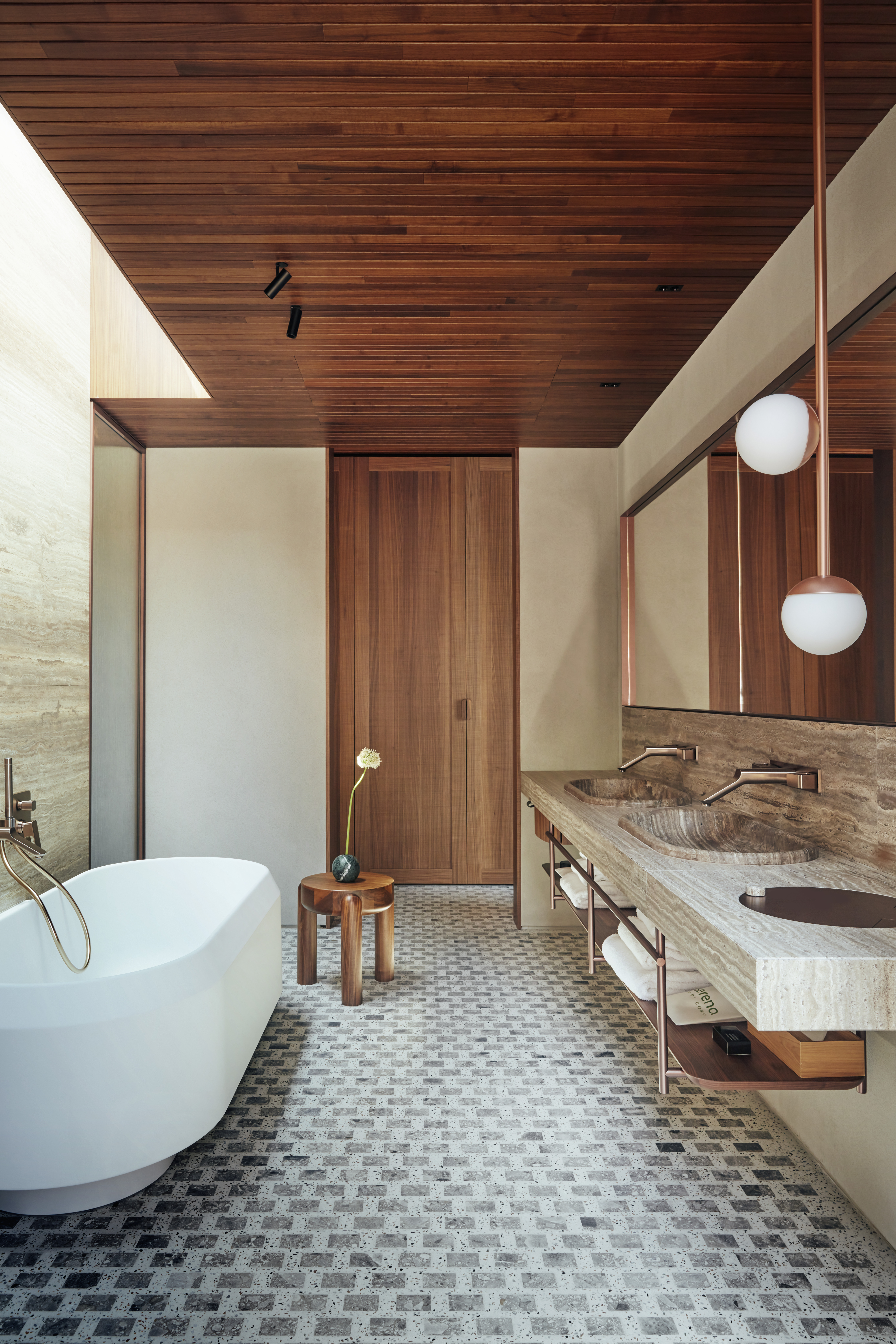Bathroom at Il Sereno Hotel penthouse with a white freestanding bathtub on the left, marble sinks on the right