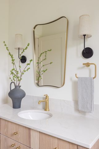 A neutral bathroom with brassy accents and warm furnishings