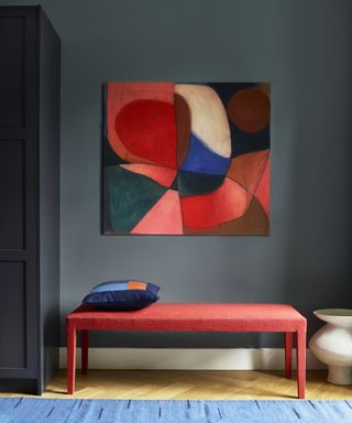 blue hallway with red upholstered bench and large abstract artwork