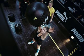 Woman throwing a medicine ball at a HYROX event