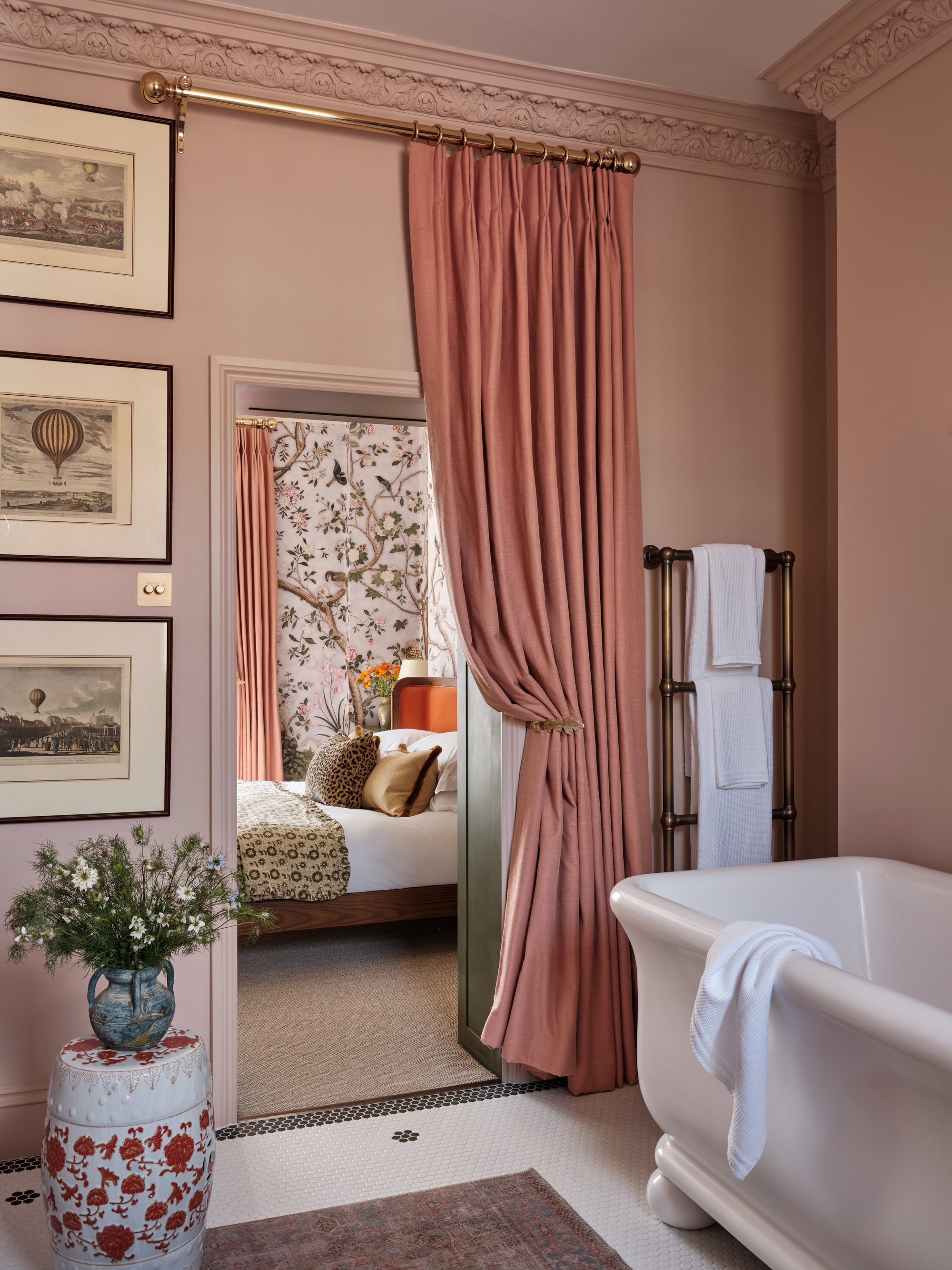 a view from a pink ensuite through to a bedroom, with a curtain across the door