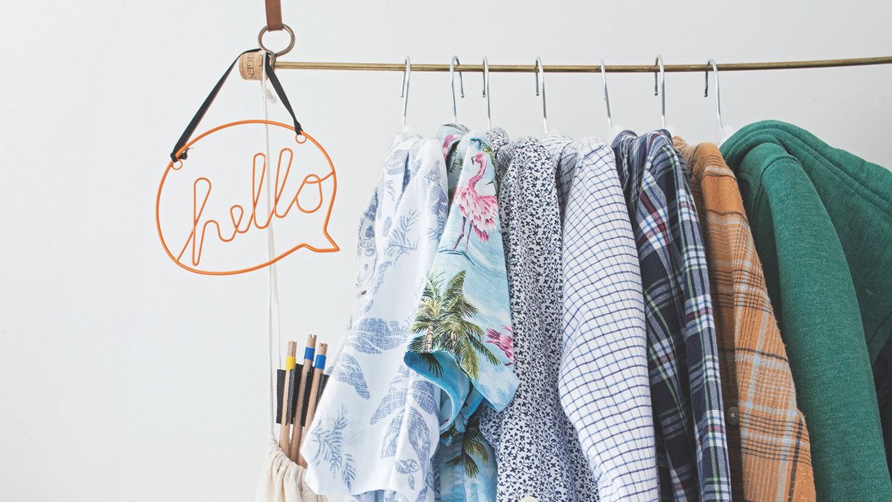 Hanging clothes rail with clothes on hangers and a wire sign that says &#039;hello&#039; on it