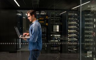 An IT technician walking past a row of data center rack servers
