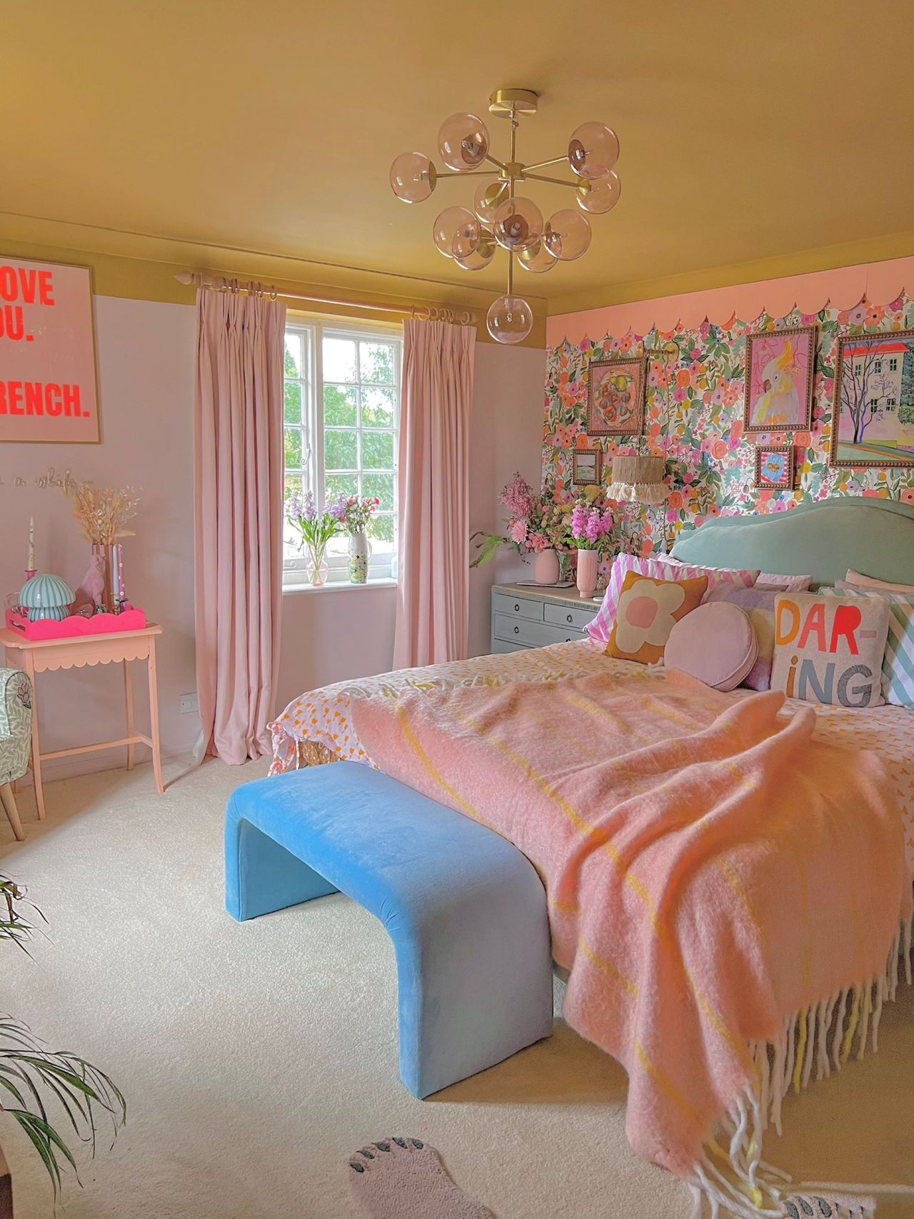 Master bedroom decorated in the style of a 'barbie' house with pink blankets, nightstand and curtains