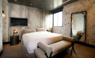 Bedroom with fog-coloured walls, wood finishes and earthy textiles