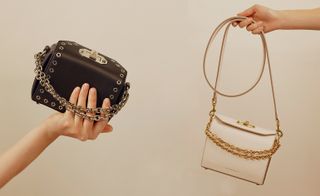 Showing Models hands holding a black box handbag and dangling a white box bag by the strap